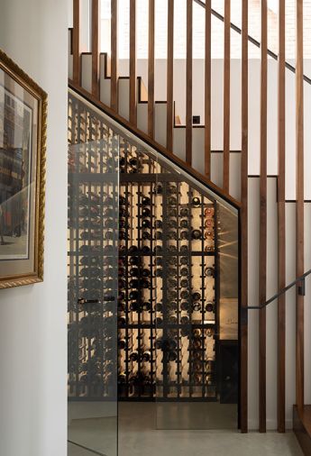 Alchemy Building Company built the custom wine system tucked under the stairs on the bottom floor. The walnut slats come down to a glass door, and the bottles are backlit for artful display.