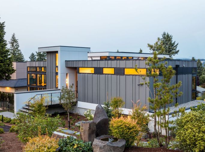 The home’s exterior is decidedly modern, including Hardi Panel and Trim Lap siding painted in a sleek Charcoal and Black Ink from Benjamin Moore. The custom door by Pivot Door Company is reached via an elevated walkway.