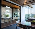 In the kitchen, white gloss upper cabinets and an opaque white glass tile backsplash from Contract Furnishings Mart are bright and modern. An extra-large island for casual family dining features elegant but durable Pental Quartz countertops and an additional prep sink.