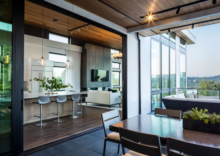 In the kitchen, white gloss upper cabinets and an opaque white glass tile backsplash from Contract Furnishings Mart are bright and modern. An extra-large island for casual family dining features elegant but durable Pental Quartz countertops and an additional prep sink.