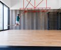 The gym’s hardwood flooring is from Fitness Flooring. The fitness space comes equipped with bright orange monkey bars, a climbing rope, and a water fountain. One side of the gym is covered in the original exterior wood siding reclaimed from the prior home.