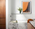 The primary bathroom combines porcelain Heska floor tile, from Emser Tile, a custom walnut and dolomite vanity, and a tub with a dolomite surround. Fireclay tile forms the backsplash, with walls painted in Benjamin Moore’s Wedding Veil.