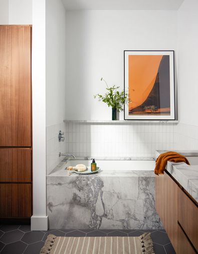 The primary bathroom combines porcelain Heska floor tile, from Emser Tile, a custom walnut and dolomite vanity, and a tub with a dolomite surround. Fireclay tile forms the backsplash, with walls painted in Benjamin Moore’s Wedding Veil.