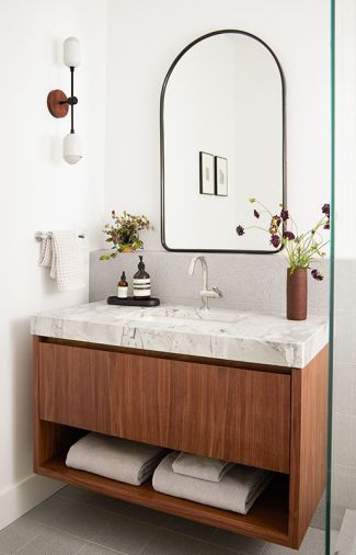 The guest bath also features a custom vanity in walnut and dolomite, with a Rejuvenation mirror, Ann Sacks floor tile, and sconce from Worley’s Lighting.