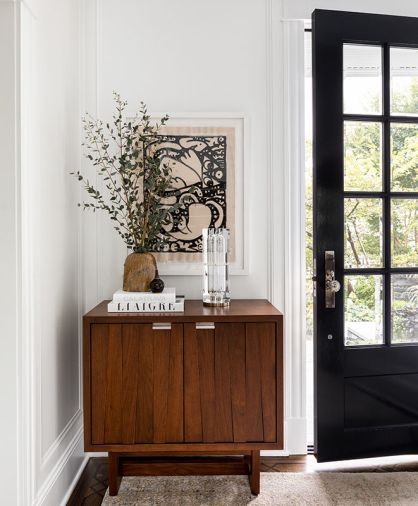 The multi-paned entry door with beveled glass by Little Pigs Distributing replaced a solid wood door to bring in light. Benjamin Moore Super White brightens home. Krieg retrofitted the Altura cabinet’s back to receive mail through the slot.