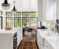 Dramatic Navy-blue pendants by The Urban Electric Co. spotlight Calacatta island. Custom corbel detail on range hood. Miele speed oven. Polished nickel Water Street Brass cabinet knobs from Chown Hardware. Driscoll Robbins Fine Carpets vintage rug reiterates Thos. Moser orange hued chair backs.