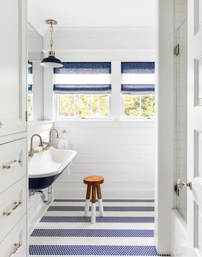 Children’s bath features blue custom painted Kohler Brockway 4' wall mounted sink against penny round mosaic floor. Urban Electric sconce painted to match. Custom Roman shades Penthouse Drapery.