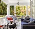 A 1920s photo revealed the current property sits on two lots, with an adjacent home apparently razed and lot purchased so this porch could be added to the south side. During trip to San Francisco, homeowners sat in the Sutherland showroom and chose the Perennial indoor-outdoor fabrics for each. Pops of blues, blacks, and orange pair with black indoor-outdoor mohair Ottoman. Orange pillows from Susan Mills at the Seattle Design Center.