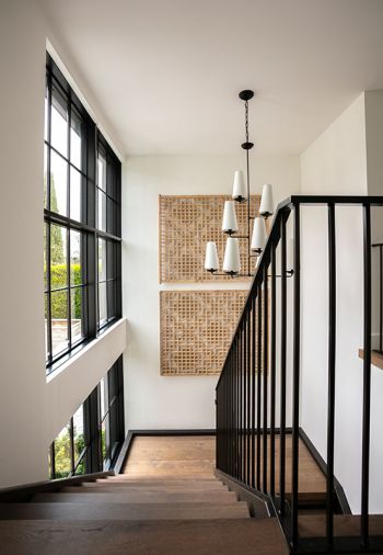 Vintage Eastern China shutters on floating staircase landing. Visual Comfort chandelier. Rhinehart Metalwork railings.