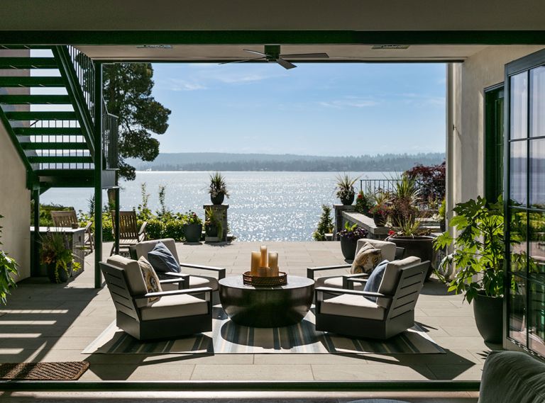 Folding Sierra Pacific door reveals entire lower-level seating area located in outdoor room. Staircase left up to back of main level. Steps up to spa at right.