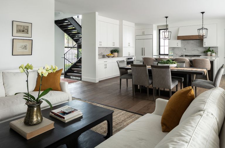 View from living room of floating staircase, dining, and kitchen layout. Sub-Zero custom paneled refrigerator. Easy-to-maintain cabinetry features hardware fit to homeowner’s hand.