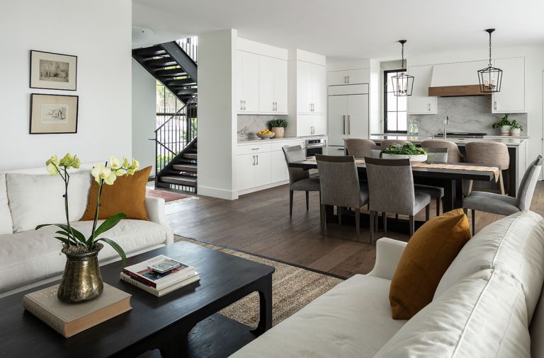 View from living room of floating staircase, dining, and kitchen layout. Sub-Zero custom paneled refrigerator. Easy-to-maintain cabinetry features hardware fit to homeowner’s hand.