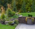 The homeowners take full advantage of their generous land, including adjacent horse and livestock pastures and barns, but the home lacked outdoor living space for entertaining and relaxing. Aerial views show how entertaining areas bring both intimacy and separation for large groups. Just past the pool deck, planters offer pops of color against natural stone retaining walls, while the addition of lush plantings soften hardscapes. Thoughtful lighting that adjusts with sunrise and sunset create a welcoming backdrop for evening gatherings.