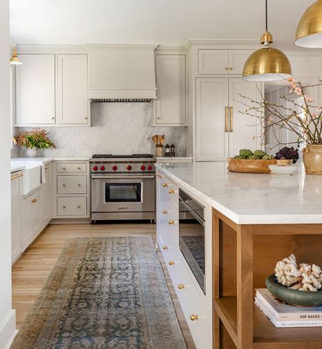 Brass Rejuvenation sconces and hardware accent custom Superior Cabinets in Agreeable Gray by Sherwin Williams. Wolf range, Carrara marble countertops, backsplash. Rohl plumbing. Found Home Shop rug.