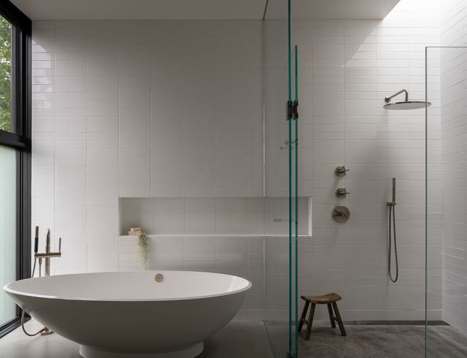 The primary bathroom is made serene with white ceramic tile, floating tub, and a curbless shower with skylight.
