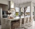 In the kitchen, the waterfall quartzite island is “Silky Polished” from Architectural Surfaces and populated with Restoration Hardware stools. Above the Miele cooktop and range, find an Olympia Tile and Stone Stilio Wave Blanco back splash by Thompson Tile.