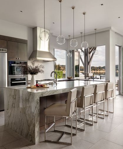 In the kitchen, the waterfall quartzite island is “Silky Polished” from Architectural Surfaces and populated with Restoration Hardware stools. Above the Miele cooktop and range, find an Olympia Tile and Stone Stilio Wave Blanco back splash by Thompson Tile.
