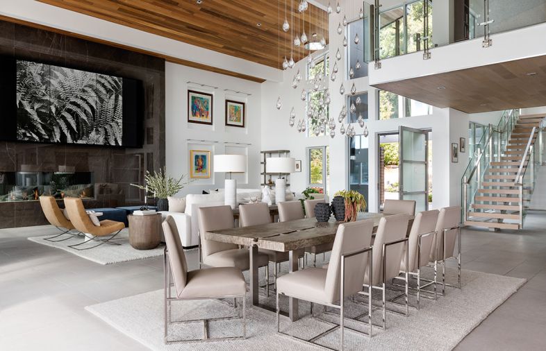 “We didn’t want anything obstructing the view,” says Meisgeier of the fixtures and furnishings. To that end, the clear glass raindrops of a custom chandelier by Studio Bel Vetro from the Kelly Forslund Showroom at Seattle Design Center maintains transparency. Low-lying furniture picks, like the Crate and Barrel leather chairs in the living room and Restoration Hardware chairs around the Williams Sonoma Home table, promote further connection to the cove outside. A custom DaVinci see-through fireplace is surrounded by Porcelanosa Savage Dark Nature tiles with subtle veining. Walls were painted Sherwin Williams High Reflective White to showcase the art.