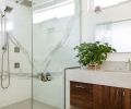 The guest bathroom is outfitted in a medley of stone and wood, including the vanity with custom black walnut Huntwood cabinets by Aimee Meisgeier and a waterfall counter in “Sea Pearl.”