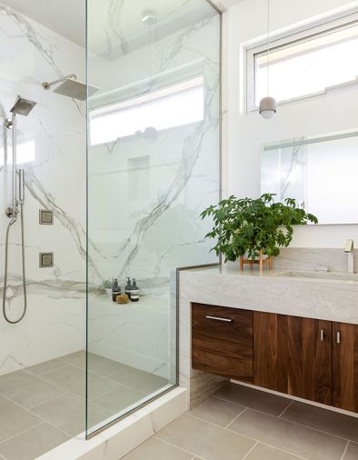 The guest bathroom is outfitted in a medley of stone and wood, including the vanity with custom black walnut Huntwood cabinets by Aimee Meisgeier and a waterfall counter in “Sea Pearl.”