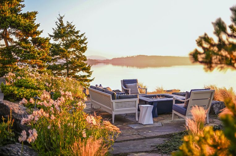 Tucked behind the main house is a waterfront terrace surrounded by naturally occurring Pinus contorta (shore pine). Shale boulders referencing the island’s actual bedrock are tucked into a host of new plantings -wavy Salmon Pink Alstroemaria “Inca Ice,” and Mexican Feather Grass. Montana Bronze Flagstone Pavers ground the terrace, where McKinnon & Harris sofa and armchairs encircle Massucco Warner’s custom designed firepit fabricated by Pepperbox. Graphic side table sourced at Perennials & Sutherland at the Seattle Design Center (SDC).