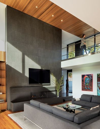 The large fireplace “anchors” the room, says Krider, who selected a custom honed Absolute Black granite slab to form the base and enclose the Napoleon Luxuria fireplace. The upper portion of the surround is clad in Flamed Absolute Granite tile through Dal Tile, for a textural contrast that creates ripples of reflected light through the space.