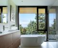 In the primary bathroom, a Victoria and Albert soaking tub is joined by a floating custom walnut vanity designed by Katy Krider Interior Design and built by OTL cabinetry.