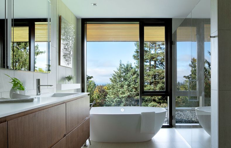 In the primary bathroom, a Victoria and Albert soaking tub is joined by a floating custom walnut vanity designed by Katy Krider Interior Design and built by OTL cabinetry.