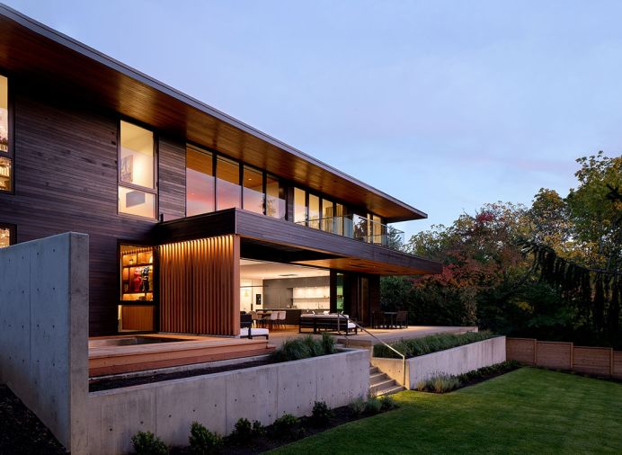 In the landscape design by Shapiro Didway, concrete planters bank the steps down to the yard. An endless pool is set into the deck, and an outdoor room tucked under cover.