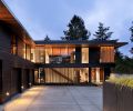 The home forms an L-shape around the auto-court, with the guest wing above the garage, and the front façade detailed with Western Red Cedar vertical slats from Lakeside Lumber.