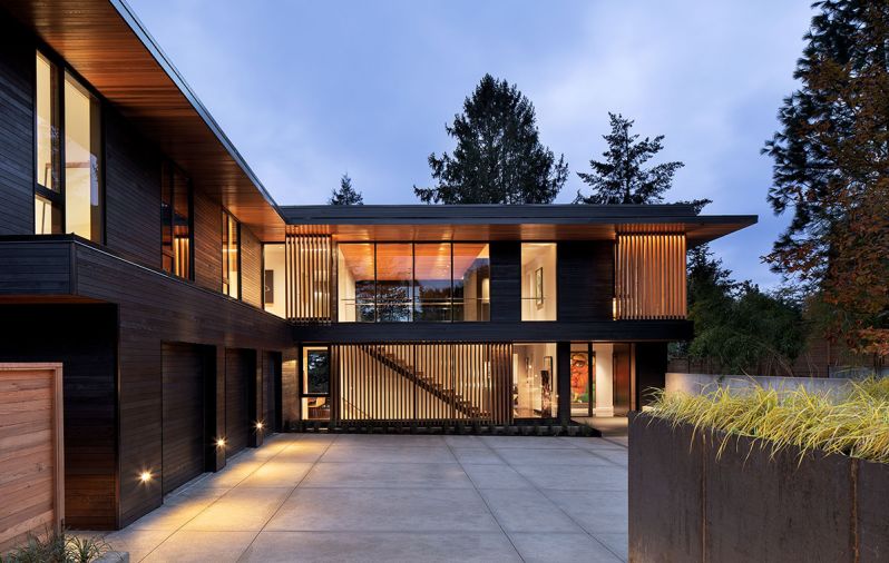The home forms an L-shape around the auto-court, with the guest wing above the garage, and the front façade detailed with Western Red Cedar vertical slats from Lakeside Lumber.
