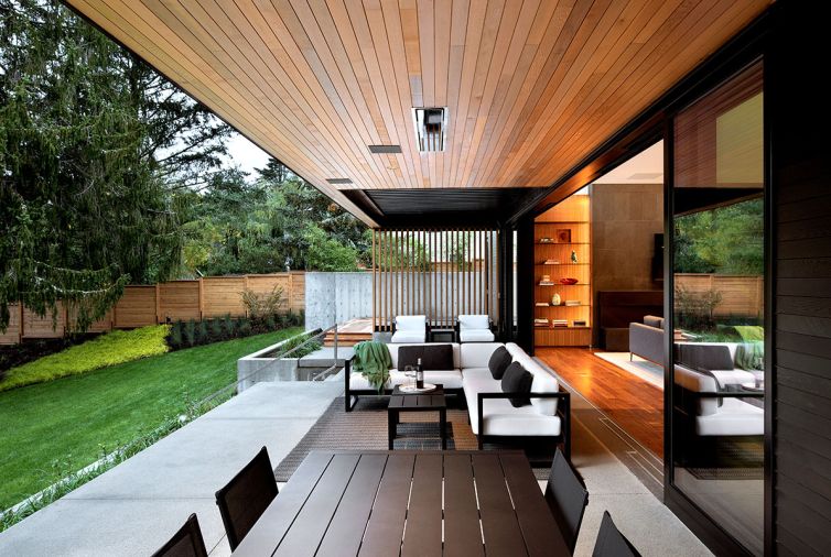 The covered outdoor room has an RH Modern outdoor sectional, tables, rug, and chairs by Restoration Hardware.