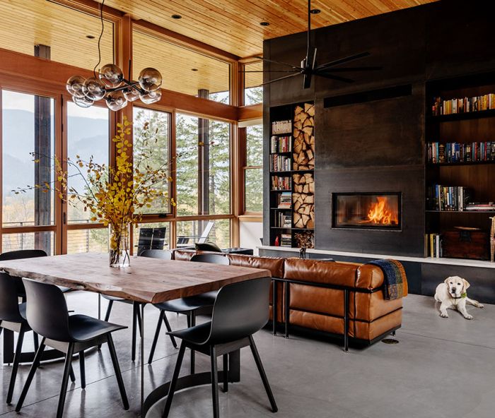 The focal point of the great room is the dramatic fireplace wall, flanked by wood storage and bookshelves. An insert from Wittus – Fire by Design is surrounded by site-built hot-rolled steel from Johnsen Steel Works. An Eternity Modern sofa sits beneath a Minka-Aire Extreme H2O Ceiling Fan. In the dining room, a Bent Dining Table from Moe’s Home Collection is surrounded by Hay chairs.