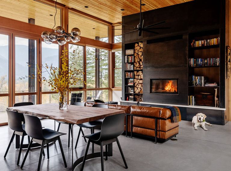 The focal point of the great room is the dramatic fireplace wall, flanked by wood storage and bookshelves. An insert from Wittus – Fire by Design is surrounded by site-built hot-rolled steel from Johnsen Steel Works. An Eternity Modern sofa sits beneath a Minka-Aire Extreme H2O Ceiling Fan. In the dining room, a Bent Dining Table from Moe’s Home Collection is surrounded by Hay chairs.
