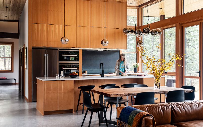 In the kitchen, the streamlined cabinetry was designed by CAST, fabricated by Custom Supplier Freeze Furniture, and paired with Quartz Pental Nordic Gray honed countertops and a site-built hot-rolled steel backsplash. A Bosch refrigerator, Miele speed oven, Monogram induction cooktop, and Miele convection oven round out the appliances. The island pendants and dining chandelier are both from West Elm, and the site-poured concrete floors throughout have radiant heat.