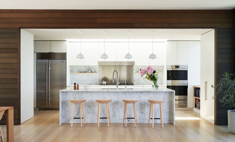 Josiah loves to cook, especially with family, so the kitchen needed to be accommodating and the dining table large enough to fit everyone. Statuary marble covers the counter, backsplash, and island, and is complemented by custom cabinets made by Dovetail, finished in a Benjamin Moore Silver Satin color. The counter stools are from Bassam Fellow and the island pendant lights by &Tradition. Appliances include a sleek Sub-Zero refrigerator and Wolf wall ovens.