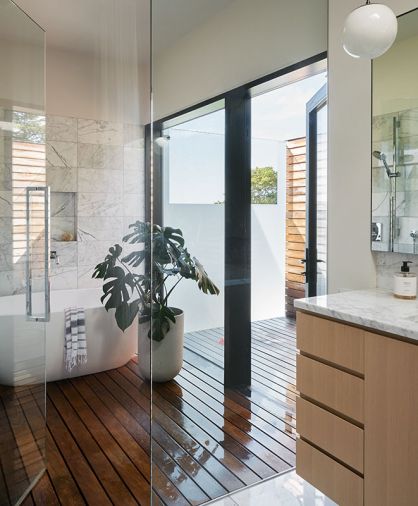 The wood flooring continues inside, and the rift white oak vanity topped in statuary marble was crafted by Dovetail.