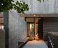 The “outdoor vestibule” includes a concrete path leading to the stained Sapele door with a hammer-formed brass pull by Dovetail. A floating Western red cedar bench is a place to pause, and the channel of river rock underneath extends into the foyer.