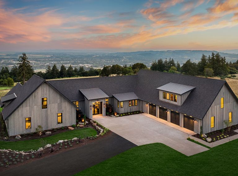 Wrapping the rustic “Hewn” Napa Valley inspired home in Hewn grey cedar siding sets it against lush green landscape and native northwest plantings. Custom double entry doors lit by gas burning lanterns open onto great room with panoramic vista. Black trimmed Marvin windows from Parr Lumber echo four-car garage doors. EV charging station.