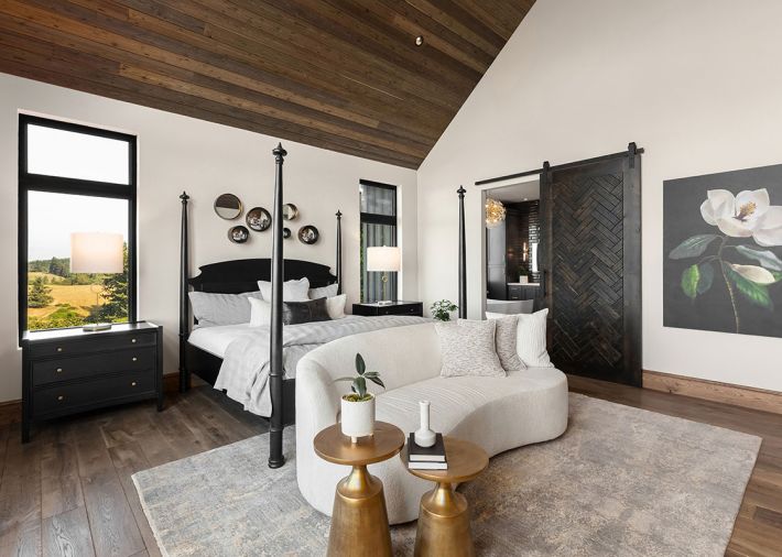 Noir bed and nightstand softened by the curve of a Bernhardt sofa facing an unseen Mutual Materials brick fireplace. Jon Dorr custom sliding barndoor adds privacy. Dalia rug from Atiyeh Bros.
