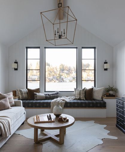 The upstairs family room has vaulted ceilings, paneled walls and Marvin windows from Portland Millwork. Charla Ray designed the custom window bench and the cushions, with fabric from Kate Ause Studio. A hide from Sadelmans and rope-wrapped lantern, from Currey and Company, bring additional texture. “Charla did such a fantastic job with all the finishes,” says Abel. “It’s very hard to do timeless.”