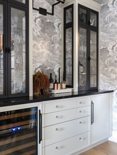 At the bar, the custom cabinetry, designed by Charla Ray and built by Rockwood Cabinetry, evokes iron and glass doors, and syncs with the black-framed windows and doors throughout. The True wine fridge is from Eastbank Contractor Appliances.