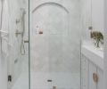 Walls are covered in Cloe Tile, and floors feature white marble mosaic flooring, both from Bedrosians. Brizo plumbing is from Consolidated Supply.