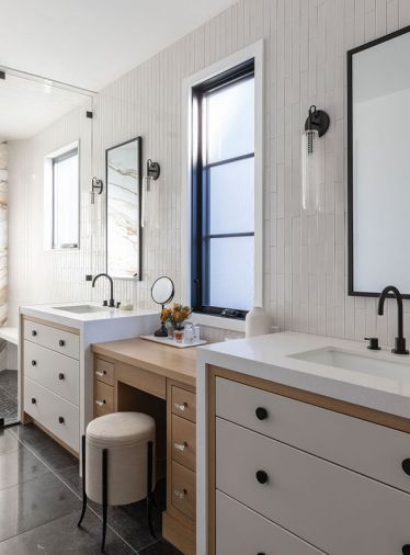 In the primary suite, the custom vanity has the same “white oak frame,” with drawers painted ‘Shaded White’ by Farrow & Ball. The walls are covered in Context Tile, while the floors have Noir Sully honed black limestone, both from Ann Sacks.