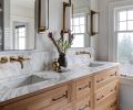 Custom cabinets in the main bath are detailed with hardware from Rejuvenation and topped with a Calacatta Marble countertop and backsplash. Waterworks plumbing from Chown and Circa Lighting are an elegant touch rooted in the aesthetic of the Jazz Age.