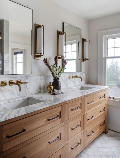 Custom cabinets in the main bath are detailed with hardware from Rejuvenation and topped with a Calacatta Marble countertop and backsplash. Waterworks plumbing from Chown and Circa Lighting are an elegant touch rooted in the aesthetic of the Jazz Age.