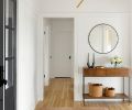 In the entry, the Simone Rug from Lulu and Georgia sits with a West Elm Industrial Storage Console and Farren Black Round Wall Mirror from CB2. A 3 Light Mini Modern Sputnik chandelier from Sputniklights shines overhead.