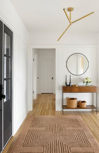 In the entry, the Simone Rug from Lulu and Georgia sits with a West Elm Industrial Storage Console and Farren Black Round Wall Mirror from CB2. A 3 Light Mini Modern Sputnik chandelier from Sputniklights shines overhead.