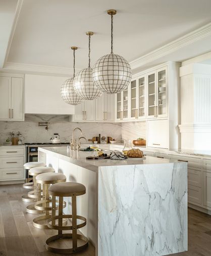 Capiz globe pendants crown Calacatta Gold island. Litze Brizo plumbing and Emtek hardware from Ferguson. Burke Décor stools by Dior.