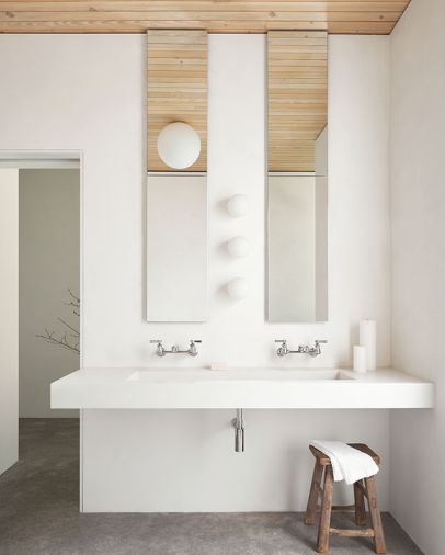 A custom cast concrete sink and clean-line fixtures from Ferguson Plumbing frame a minimalist bathroom with room for future cabinetry if desired.